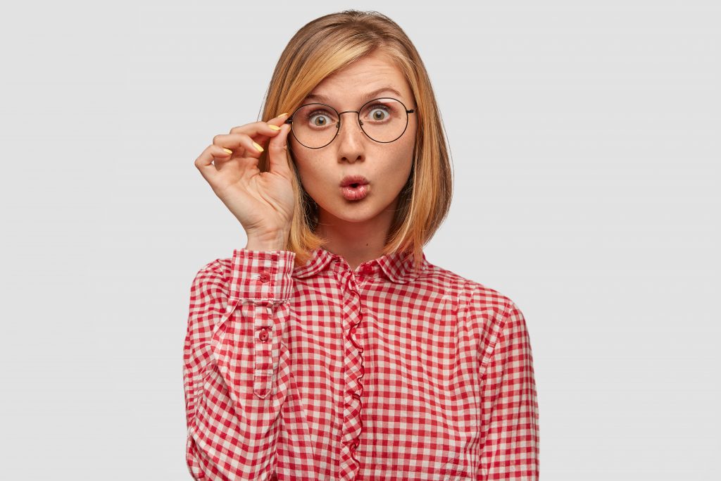 surprised woman with european appearance being stupefied by sudden news world stares through glasses